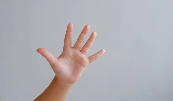 hand with stop gesture on grey background. numeric five.