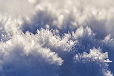 Güneş ışığı altındaki parlak kar tanelerinin yakın görüntüsü. Kışın zarif şablonları. Parlayan karın makro görüntüsü.