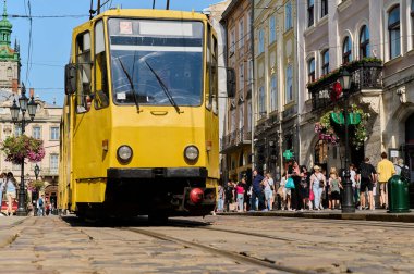 Kalabalık bir şehir caddesinde gün boyunca eski sarı tramvay