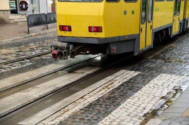 Gri şehir caddesinde eski sarı tramvay yağmurdan sonra, şehir klasik treni
