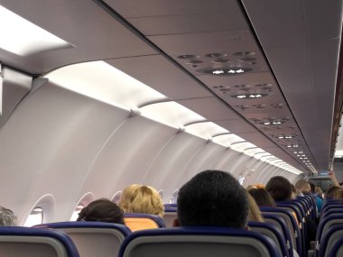 Arkadan gelen insanlarla dolu bir uçakta yolcu koltuğu, cep telefonu fotoğrafı.