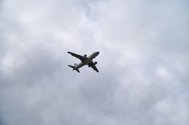View of an airplane in the sky in cloudy weather flying to the right