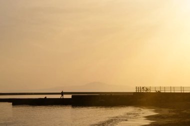 Silhouette of a man walking next to the sea during the sunset