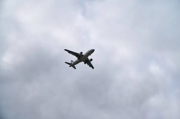 View of an airplane in the sky in cloudy weather flying to the right