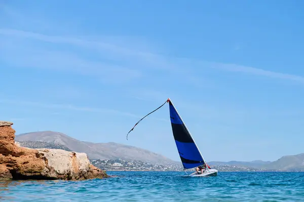 Windsurfing in azure sea, mountains background