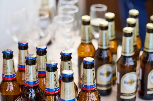 Ukrayna 11.04.2024 warsteiner birası. Alkolsüz bira. Masadaki sıra sıra dizilmiş şişelerle tıpalanmış. Arka planda bira bardakları
