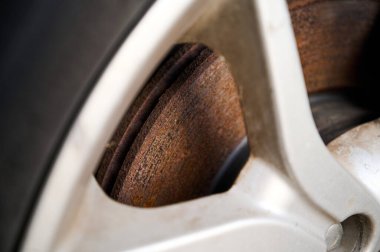 Paslı fren diski alaşımlı tekerleklerin arasından dışarı bakıyor. Eski tekerlek. Yakın plan.