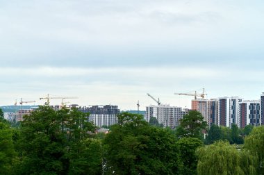 İnşaat vinçleri şehirdeki inşaat sahasında. Şehirde konut inşaatı