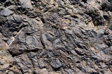 Karmaşık kaya oluşumlarının çarpıcı bir görüntüsü koyu taş katmanlarını desen ve renk çeşitliliğiyle sergiliyor. Bu jeolojik özellik zaman içindeki doğal süreçleri temsil eder..