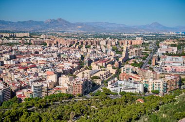 Dağlar ve yemyeşil yeşilliklerle çevrili renkli binalarla dolu canlı kentsel bir alana bakan güneşli bir günde Valencia 'nın güzelliğini gözler önüne seriyor. Alicante, İspanya 10.01.2023