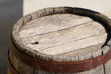 Sıcak güneş ışığında dinlenen yıpranmış ahşap fıçı kırsal cazibesini çatlak bir yüzey ve demir bantla sergiliyor. El işçiliği ve geçen zaman hakkında hikayeler anlatıyor..