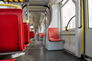 Boş kırmızı koltukları ve geniş pencereleri olan parlak ve temiz bir ulaşım aracının içi geniş bir atmosfer yaratır..