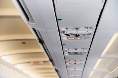 Bir uçak kabinindeki kontrol paneli yolcuların güvenliği için uçuş sırasında ışık ve kontrolleri gösteriyor..