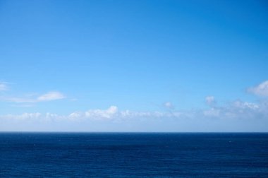Uçsuz bucaksız okyanus mavi gökyüzü ile kabarık bulutlar bir araya gelir ve dingin bir atmosfer yaratır..