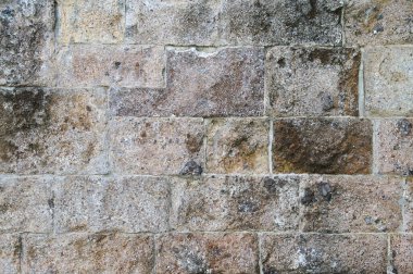 Açık hava ortamında çeşitli tonları ve desenleri olan desenli taş bir duvarın yakın görüntüsü.