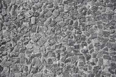 Çeşitli düzensiz taşlardan yapılmış, benzersiz bir desen ve doğal güzelliği gösteren dokulu bir duvarın yakın görüntüsü..