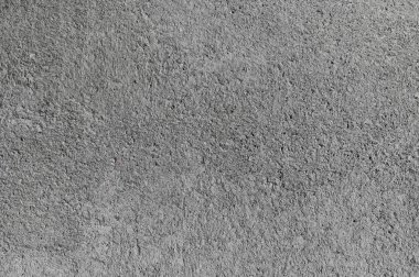 Detaylı beton yüzey parlak gün ışığında çatlaklar ve doku gösteriyor, yaşlanma ve yıpranma vurgulanıyor.