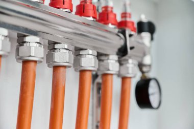 Turuncu borular, metal tesisatlar ve ölçümler için basınç göstergesinden oluşan bir tesisat düzeneğinin yakın çekimi..