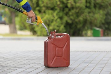 A man fills jerry cans at a gas station. A man fills gasoline in a canister at a gas station. Pouring gasoline into a canister. Collecting funds to buy fuel.