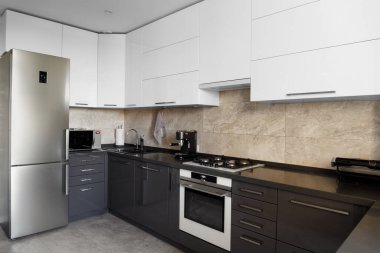 The kitchen in the apartment. The design of the kitchen room. Gray kitchen interior with white cabinets. Built-in oven in the interior of the kitchen.. Kitchen interier.