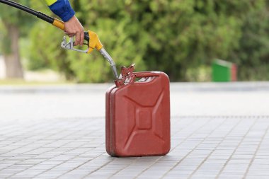 A man fills jerry cans at a gas station. A man fills gasoline in a canister at a gas station. Pouring gasoline into a canister. Collecting funds to buy fuel.