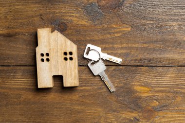 Conceptual image of a small house and keys on a wooden surface with space for text. Property For Sale. House sale advertisement. Keys to your dream house.