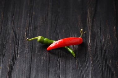 Red and green chili peppers on a dark wooden background close-up. Spicy food. Ingredients for spicy food. Multi-colored hot pepper on a black background.