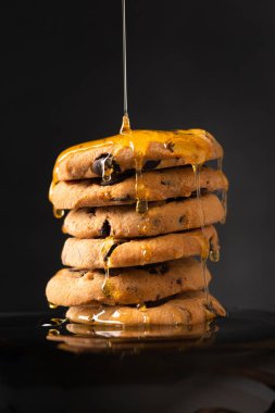 Cookies with honey on a black background. Homemade cookies and honey. Honey pours on cookies side view. Sweet breakfast. Dessert.