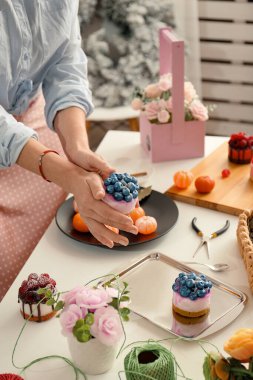 Handmade soap. Home made soap look like cake with berries on light background. Natural homemade cosmetics and handmade soaps concept. The girl is holding a homemade muffin in her hands