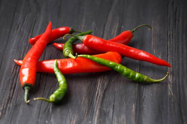 Chili pepper on a wooden background close-up. Several pods of hot red and green peppers on the table
