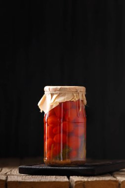 Canned tomatoes. Pickled tomatoes in a jar. Sliced tomatoes in a marinade on a wooden background. tomatoes appetizer. canned salad.