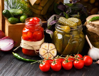 Canned tomatoes in closed jars with spices on a wooden background. Harvesting tomatoes for the winter. Canning tomatoes with garlic, pepper, dill and basil.