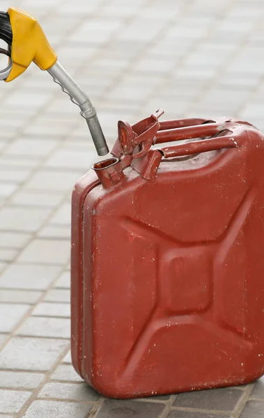A man fills jerry cans at a gas station. A man fills gasoline in a canister at a gas station. Pouring gasoline into a canister. Collecting funds to buy fuel.