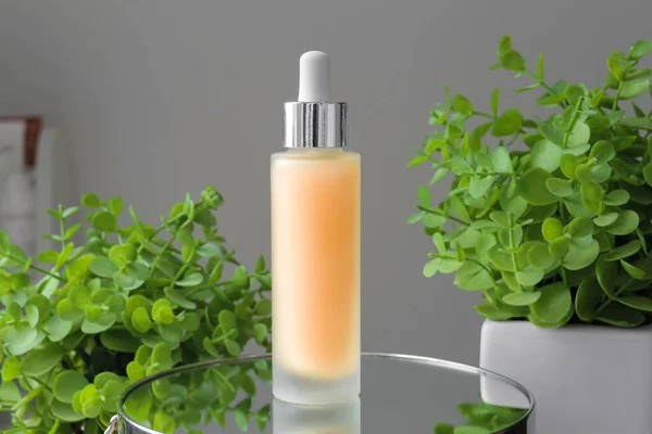 Cosmetics on a mirror surface. Serum for the face on a green background. Body cosmetics on a gray background. Face and body care. Professional cosmetics.