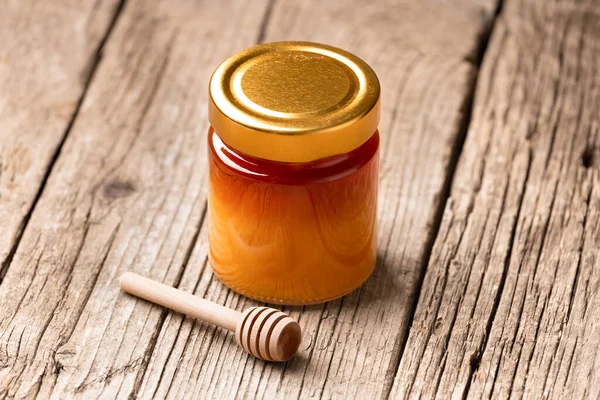 Honey in a closed glass jar and a bowl on a wooden background. Composition of honey jars and dipper. Healthy foods. organic honey. Organic products.