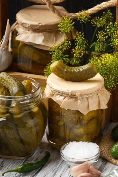 Pickled cucumbers in a jars on a dark wooden background. Homemade marinated cucumbers. Pickled cucumber salad in a jar.