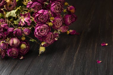 Koyu ahşap arka planda bir buket kuru pembe gül. Yalnızlık ya da yaş kavramı. Üzüntü, mutsuz aşk.
