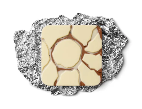 Chocolate on silver foil unfolded top view. A bar of chocolate lies on a foil on insulation. Unwrapped chocolate on silver foil on a white background.