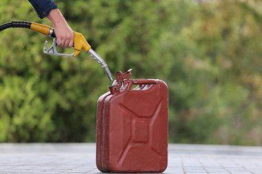 A man fills jerry cans at a gas station. A man fills gasoline in a canister at a gas station. Pouring gasoline into a canister. Collecting funds to buy fuel.