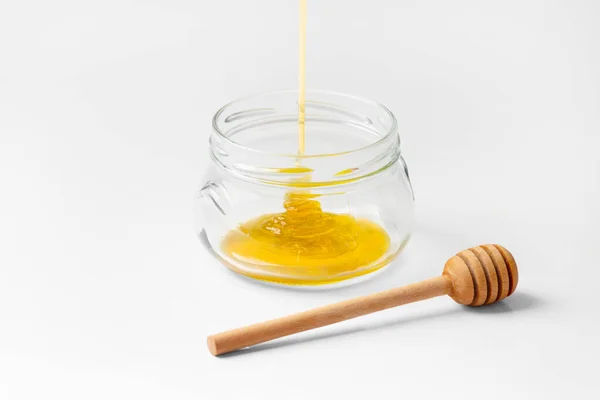 Honey Poured Empty Glass Transparent Jar Wooden Dipper White Background — Stockfoto