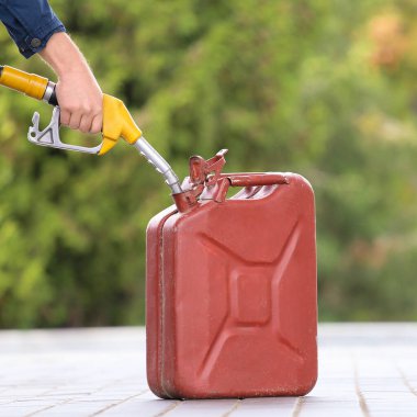 A man fills jerry cans at a gas station. A man fills gasoline in a canister at a gas station. Pouring gasoline into a canister. Collecting funds to buy fuel.