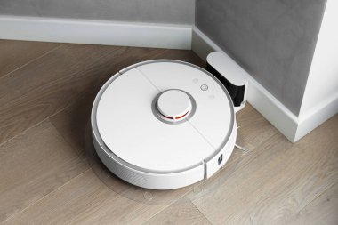 Beyaz robot elektrik süpürgesi yanaşma istasyonunda şarj oluyor. Akıllı temizlik, akıllı otomatik elektrik süpürgesi içerideki şarj istasyonuna bağlı..