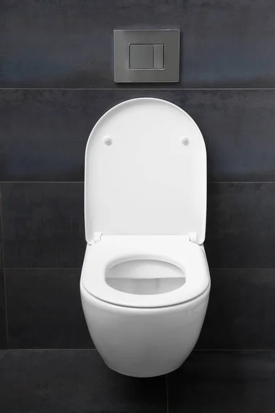 現代的な壁に取り付けられた白いトイレで 座席を下げ 蓋を上げ 黒い壁に対して光沢のあるクロムフラッシュボタンを備えています 浴室内の便器と設置 — ストック写真