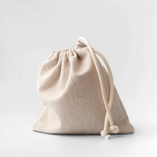 Tied small bag made of natural fabric on a white background. Cotton bag with drawstrings on insulation. Pouch in coarse fabric with drawstrings. Closed fabric bag.