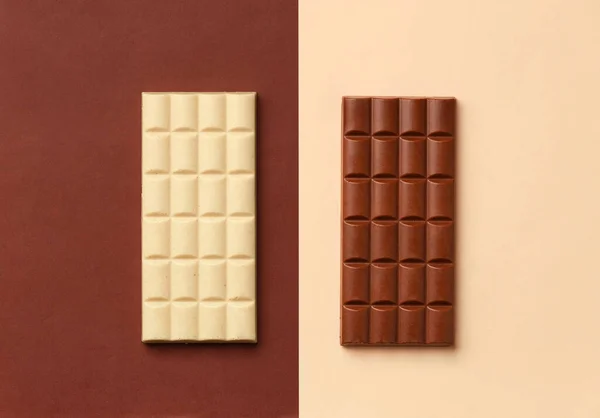 White chocolate bar on a brown background, milk chocolate bar on a beige background top view, chocolate on contrasting backgrounds.