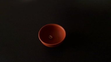 Tuzlu şam fıstıkları, siyah arka planda, yavaş çekimde kilden bir kaseye düşer..