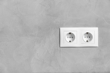 Gri desenli duvarda plastik beyaz çift elektrik prizi ve metin için yer var..