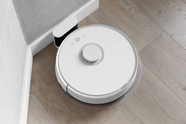 Beyaz robot elektrik süpürgesi yanaşma istasyonunda şarj oluyor. Akıllı temizlik, akıllı otomatik elektrik süpürgesi içerideki şarj istasyonuna bağlı..