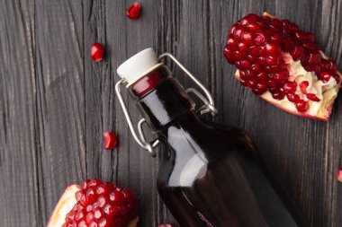 Olgun kırık nar, dağınık büyük taneler, taze sıkılmış nar suyu şeffaf bir şişede ahşap arka plan manzarasında. Nar ve nar suyunun yaratıcı bileşimi.