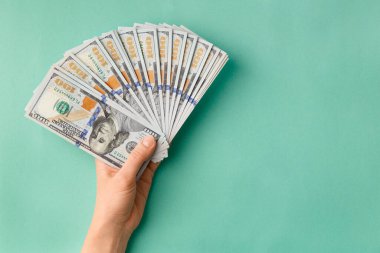 100 dolarlık banknotların çoğu yeşil arka plan manzaralı bir vantilatörde katlanmış ve mesaj için boşluk bırakılmış. Para, banknotlar kadınların elinde. Başarı, iş, zenginlik kavramı.